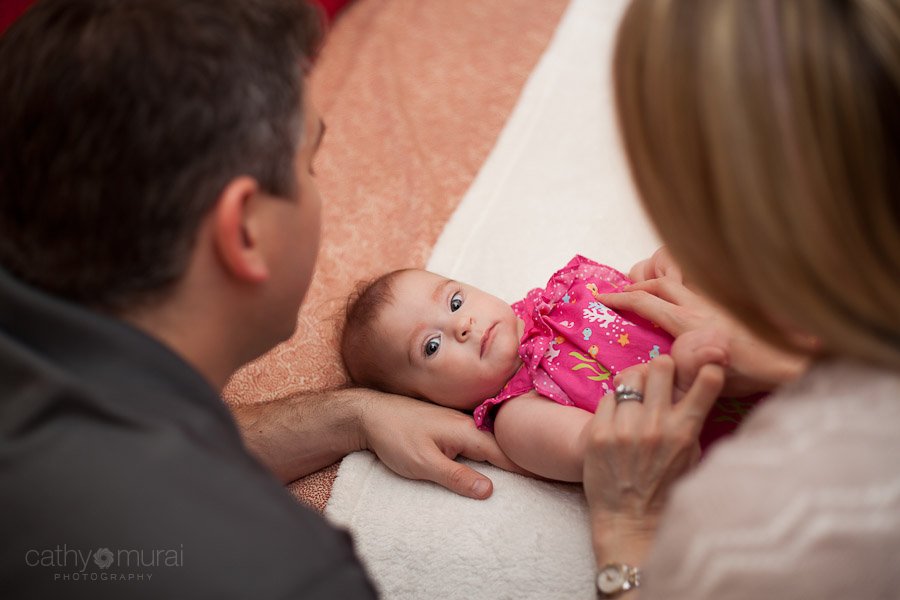 An adorable baby looking at the camera through her parents - Captured by a Glendale Lifestyle Baby Photographer, Cathy Murai Photography