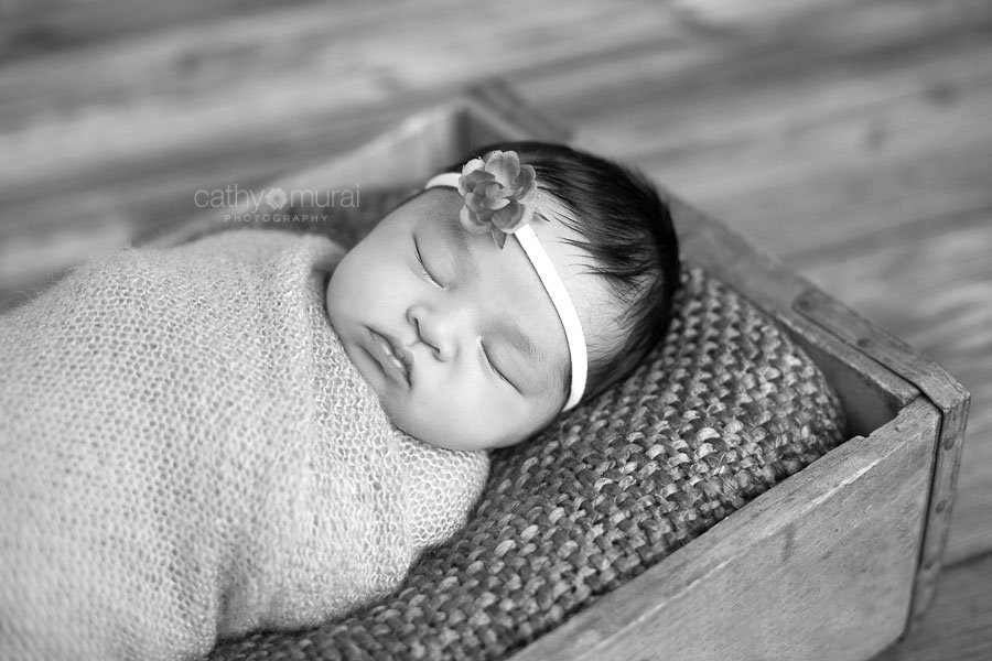 Precious Asian Newborn Baby Girl wrapped with pink stretched wrap sleeping in the antique soda box in the black and white picture captured by Pasadena, Alhambra, San Gabriel Valley Newborn Photographer, Pet Photographer, Family Photographer, Cathy Murai Photography