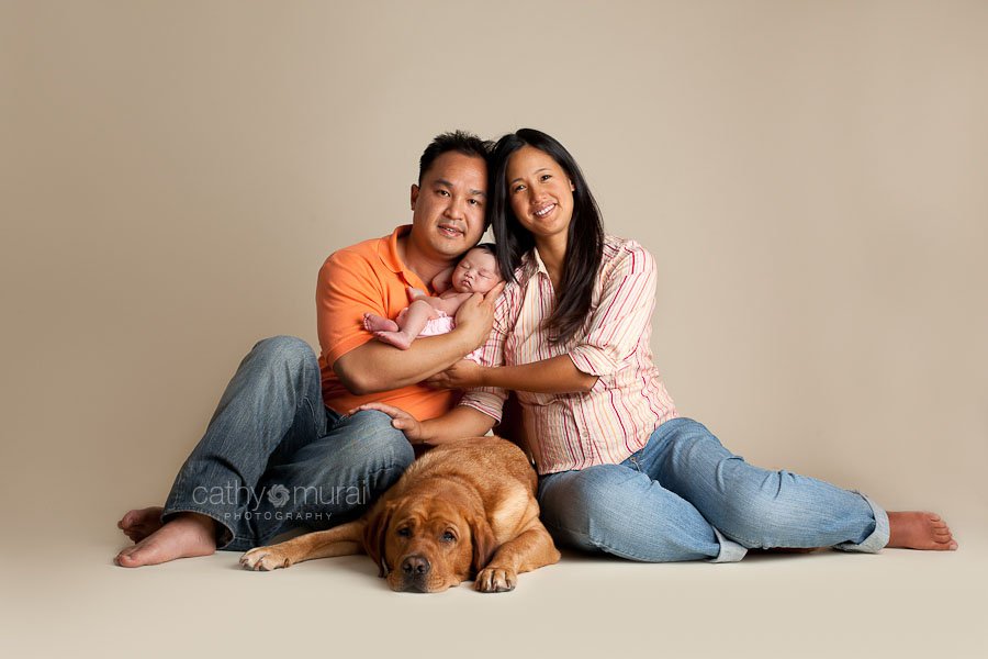Precious Asian Newborn Baby Girl in a pink diaper sleeping in the family portrait, which includes the mom, dad, and her family dog, a Labrador, in the picture captured by Pasadena, south Pasadena, Alhambra, San Gabriel Valley Newborn Photographer, Pet Photographer, Family Photographer, Cathy Murai Photography