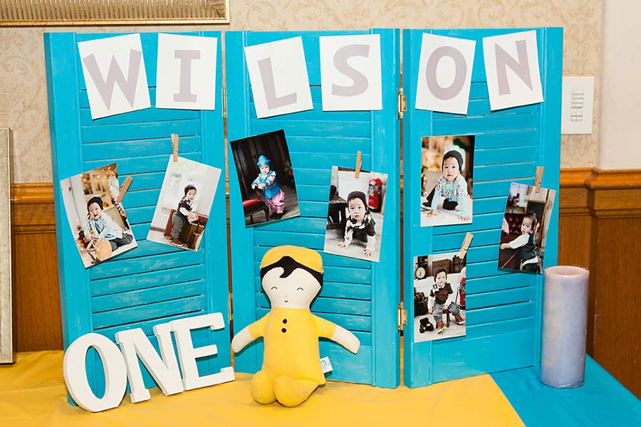 Display pictures of the baby on the blue shutters with the letter ONE and Dr. Suess yellow doll on the photo table