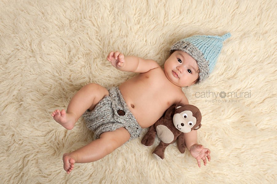 100 days old celebration, Asian Baby, 3 months old baby portraits,  3 months old baby picture, 100 day old,  baby boy,  3 months old baby image, Cathy Murai Photography, Alhambra, Baby, Photographer, Photography, San Gabriel Valley, Los Angeles,  a baby wearing a blue and grey knit hat and grey diaper cover is holding his stuffed animal (monkey)  and  looking at the camera, Baby Photography Session 