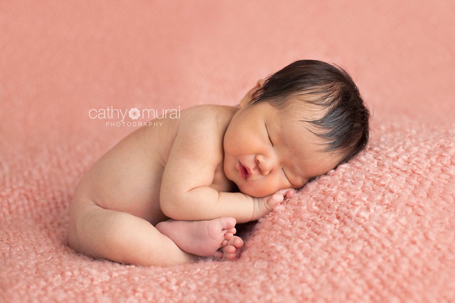 A beautiful 8 day old Asian newborn baby girl sleeping necked on the peach pink bean bag blanket, Taco pose, A newborn baby portrait taken in the studio during newborn portrait session by Los Angeles, San Gabriel Valley, Alhambra Newborn Photographer, Cathy Murai Photography