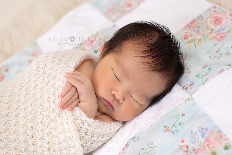 A beautiful 8 day old Asian newborn baby girl wrapped with a handmade blanket crochet by the grandma.  A baby sleeping on the handmade quilt blanket. A newborn baby portrait taken in the studio during newborn portrait session by Los Angeles, San Gabriel Valley, Alhambra Newborn Photographer, Cathy Murai Photography