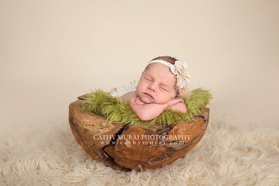 Precious Newborn Baby Girl wearing a cream flower headband posing on green fur Los Angeles. Pasadena, Newborn photographer, Cathy Miurai Photography 