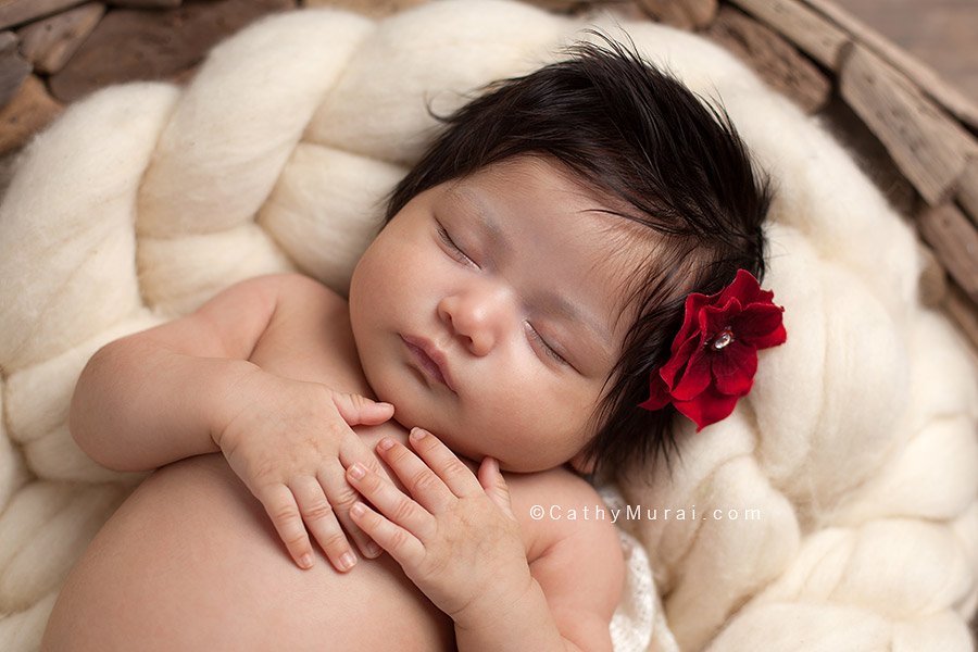 6 weeks old newborn baby girl, wearing a red flower, sleeping on her back, posing with both hands, on the puzzled basket, wooden floor, newborn portrait photography, Captured by Los Angeles, Alhambra Newborn Photographer, Cathy Murai Photography