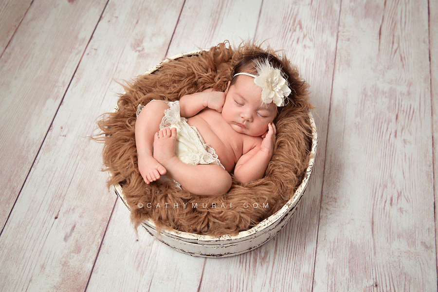 Newborn Baby Girl wearing white headband sleeping on brown fury in white basket, Los Angeles Newborn Photographer, Cathy Murai Photography, Alhambra, Las Tunas, San Gabriel Valley