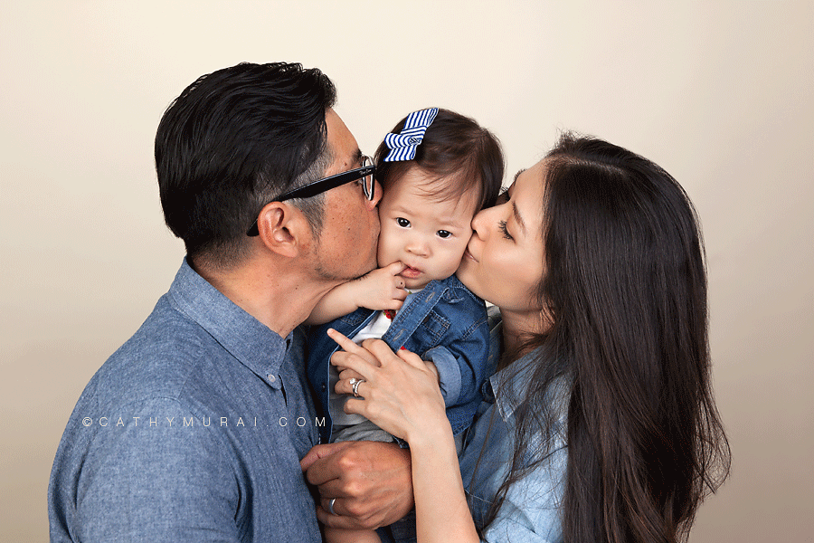Parents kissing their daughter's cheeks, family kissing picture taken during first birthday portrait session, 1st birthday portrait session