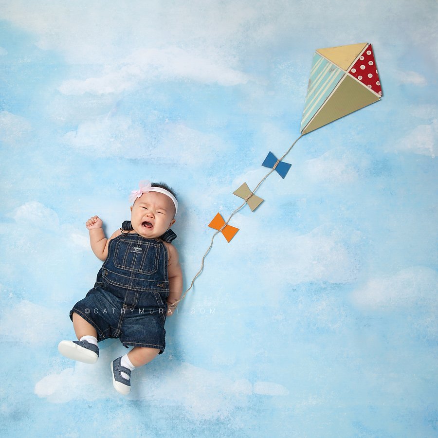 Crying 3 month old baby, Crying 3 months old baby girl holding a kite in the sky