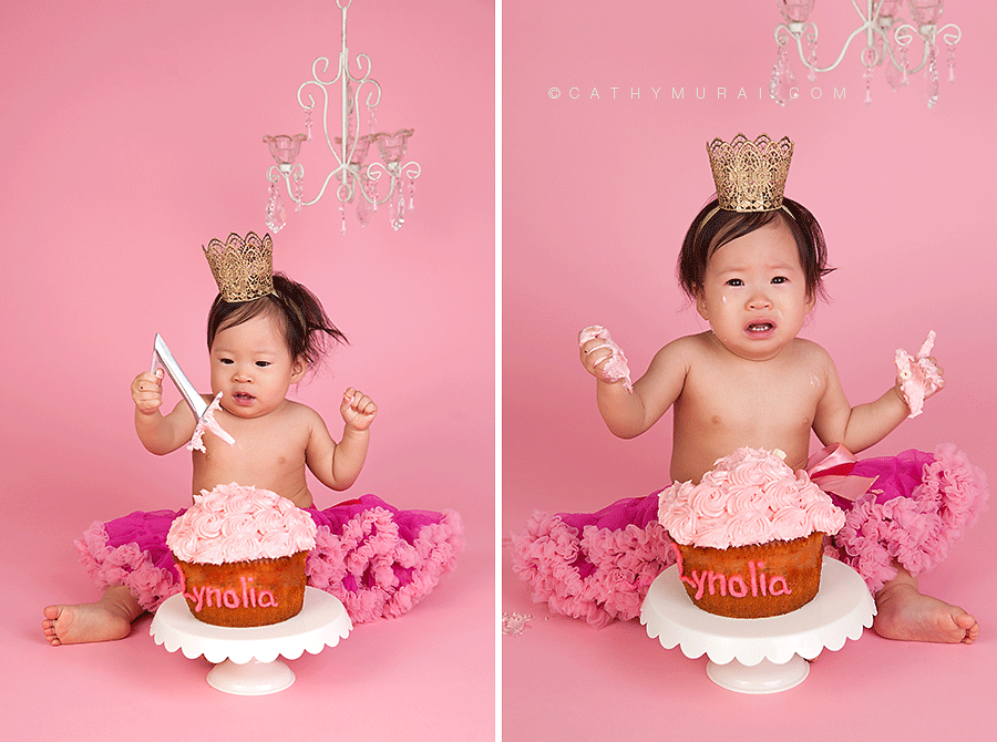 Adorable one year old girl hearing a gold crown and pink pettiskirt, crying during smash cake session, cake smash session, personalized pink giant cupcake, chandelier prop