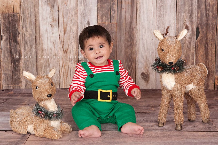 baby elf sitting and smiling next to reindeers on the wooden floor and wooden backdrop, Christmas Baby Portrait Session, Los Angeles Christmas Baby Portrait Session, Alhambra Christmas Baby Portrait Session, Pasadena Christmas Baby Portrait Session, South Pasadena Christmas Baby Portrait Session, Las Tunas Christmas Baby Portrait Session, Rosemead Christmas Baby Portrait Session, San Marino Christmas Baby Portrait, El Monte Christmas Baby Portrait Session, South El Monte Christmas Baby Portrait Session, San Gabriel Valley Christmas Baby Portrait Session, Monrovia Christmas Baby Portrait Session, Glendale Christmas Baby Portrait Session, North Hollywood Christmas Baby Portrait Session, Los Angeles Christmas Baby photographer baby Christmas Baby photographer, Los Angeles Christmas Baby baby photography, famous baby photographer, famous Christmas Baby photographer, los Angeles best Christmas Baby photographer, Los Angeles Christmas Baby photography, los Angeles Christmas Baby photographer, los Angeles, Christmas Baby photography, Alhambra, Christmas Baby photography, Pasadena Christmas Baby baby photographer, Pasadena Christmas Baby photographer, San Gabriel Valley Christmas Baby photography, San Gabriel Valley Christmas Baby photographer, Alhambra Christmas Baby photography, Las Tunas Christmas Baby photography, Las Tunas Christmas Baby photographer, Baby Studio photography